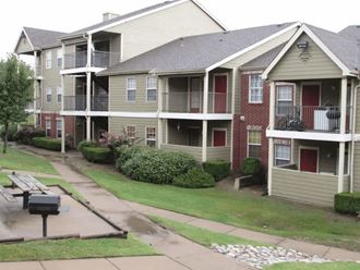 an apartment complex with a bench in front of it at GABLE HILLS Apartments, TULSA, OK, 74127