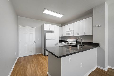 a kitchen with white cabinets and a black counter top at K Street Flats, Berkeley, 94704