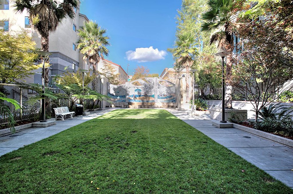 a grassy area with a mural on the side of a building at K Street Flats, California, 94704