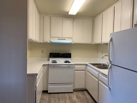 A kitchen with white cabinets and appliances.