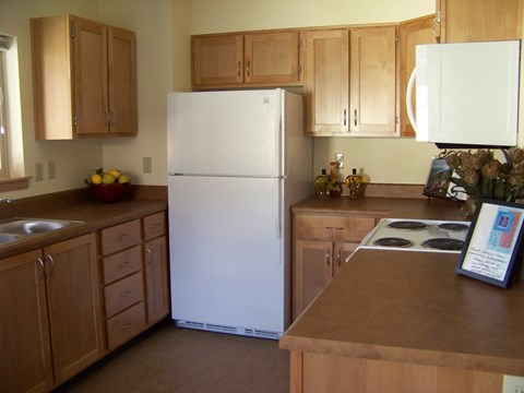 A white refrigerator in a kitchen with wooden cabinets.