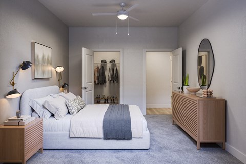 A bedroom with a large bed and a clothing rack in the background.