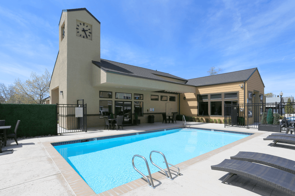 Apartments For Rent In Sparks, NV - Fountainhouse at Victorian Square - Gated Sparkling Pool With Lounge Chairs, Tables, And Access To Clubhouse With A Clock Tower