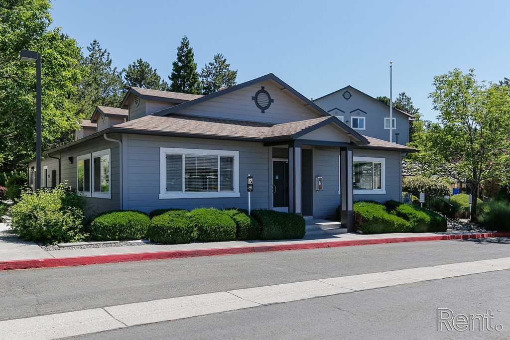 a gray house with a brown roof and a red curb