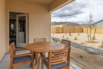 a patio with a wooden table and chairs in front of a sliding glass door