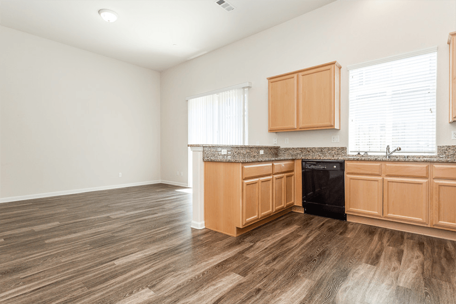 Apartments In Rocklin For Rent - Dining And Kitchen Area With Wood Flooring, Sliding Doors To Patio, Wood Cabinets, Sink, And Dishwasher.
