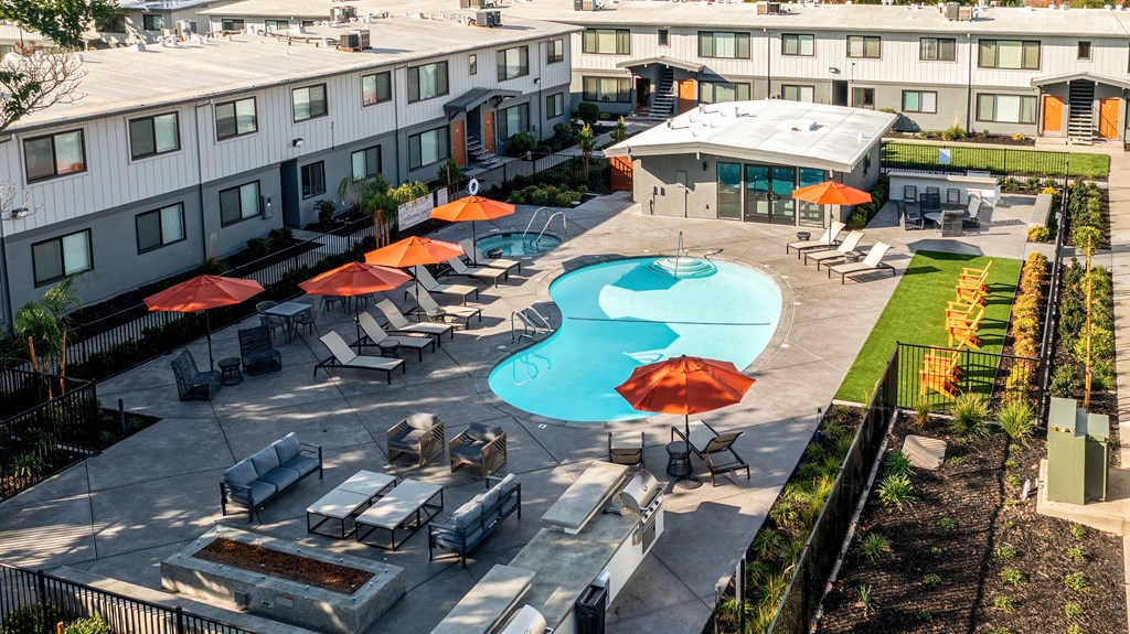 an aerial view of a swimming pool and patio with umbrellas