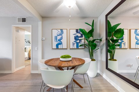 A dining room with a wooden table and white chairs.