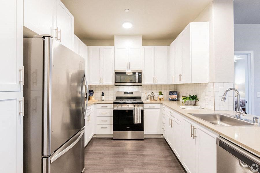 3 BR Apartments in Roseville CA - Harvest at Fiddyment Ranch - Modern Kitchen with Stainless-Steel Appliances, White Cabinetry, and Wood-Style Flooring
