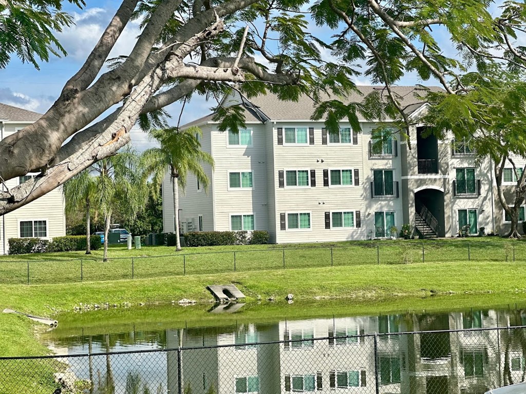A large white building with a green lawn in front at Hawk's Landing Apartments, Florida
