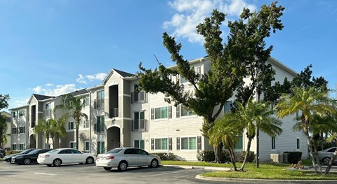 A white building with a parking lot in front of it at Hawk's Landing Apartments, Fort Myers, Florida