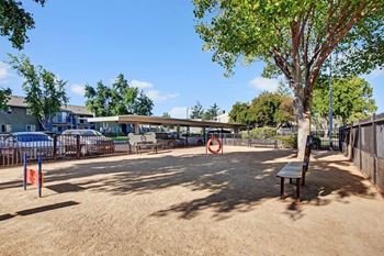 A playground with a red and white sign, a bench, and a tree.
