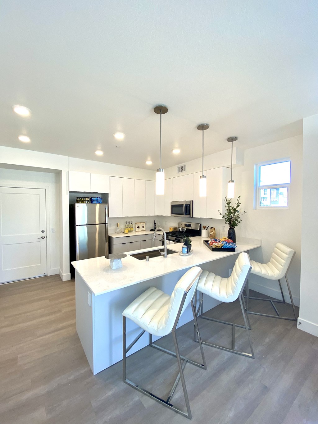 a kitchen with white cabinets and a large island with white chairs