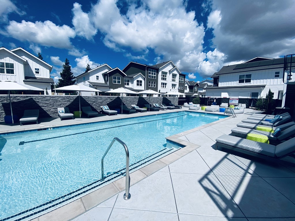 Apartments for Rent Vacaville CA - The Preserve at Harbison - Resort-Style Pool Area with Lounge Chairs, Tables, and Umbrellas