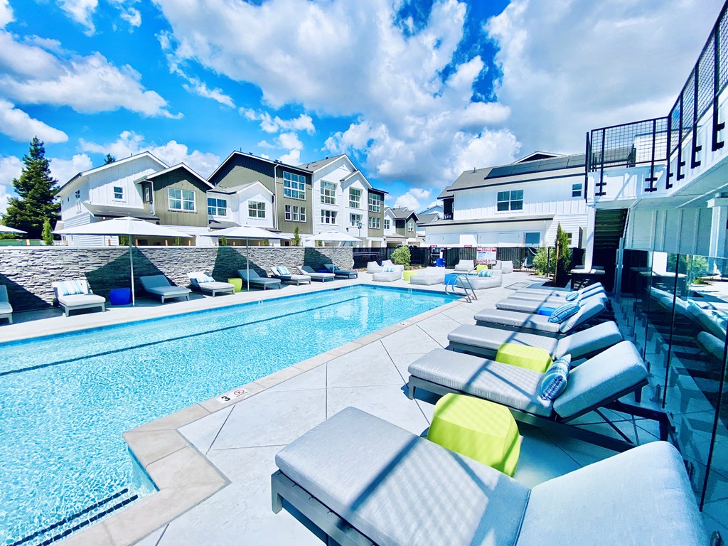 Apartments for Rent Vacaville CA - The Preserve at Harbison - Resort-Style Pool Area with Lounge Chairs, Tables, and Umbrellas