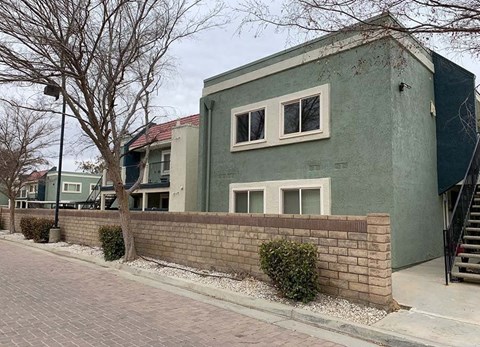 a green house with a brick wall in front of it