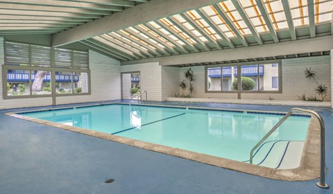 A swimming pool inside a building with a skylight above it.
