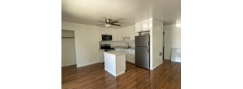 an empty kitchen with white cabinets and a stainless steel refrigerator