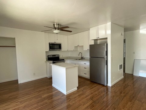 an empty kitchen with white cabinets and a stainless steel refrigerator