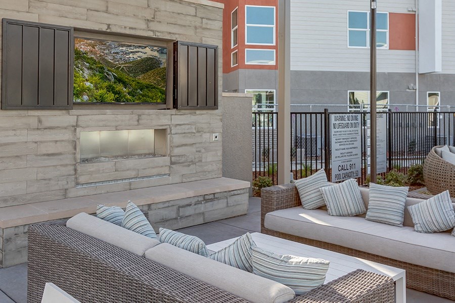 Apartments for Rent in Folsom - Hub Apartments - Outdoor Fireplace, Seating Area, Blue Decorative Pillows, and a White Table