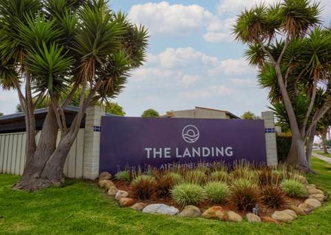 A sign that says "The Landing" is in front of some trees.