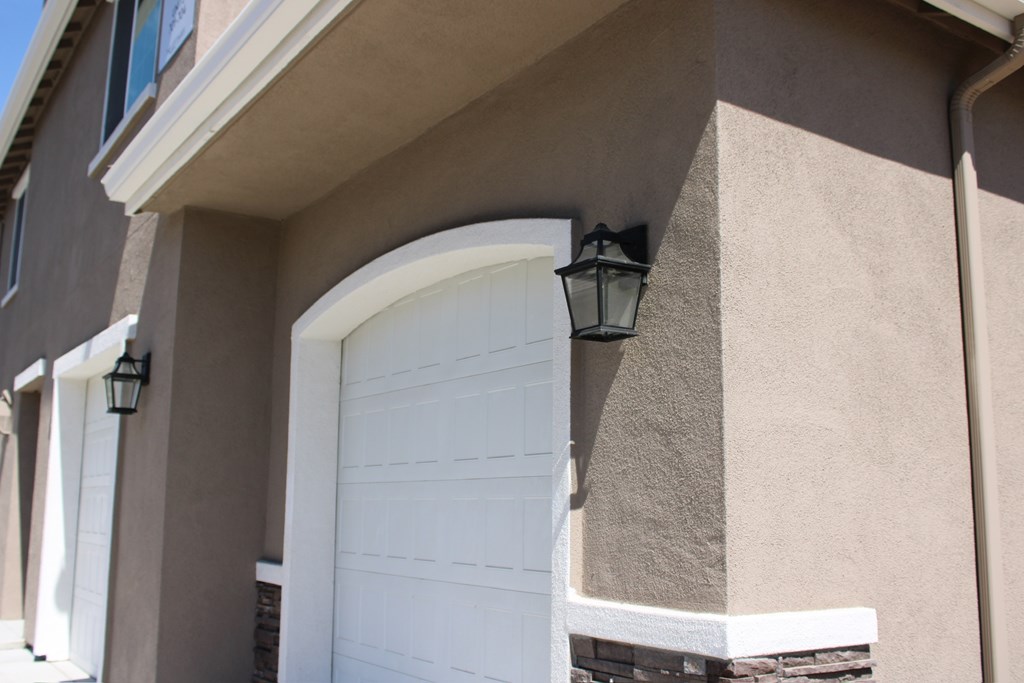 A white garage door is attached to a tan house.