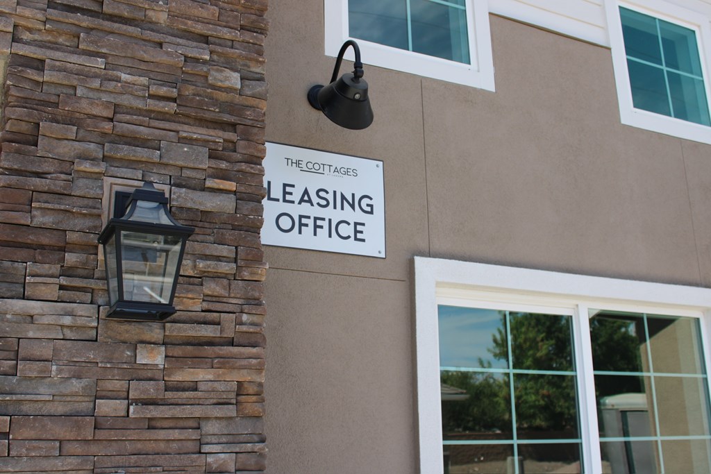 A sign that says "The Cottages Pleasing Office" is on a building.