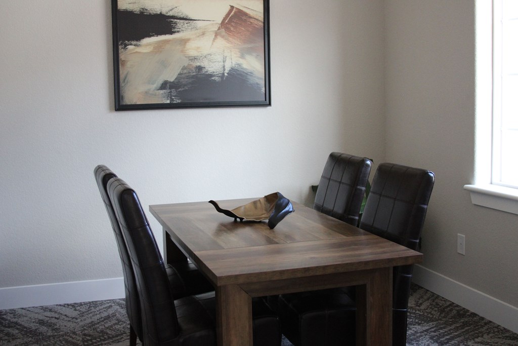 A wooden dining table with four chairs and a bowl on it.
