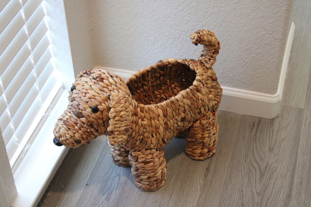 A tan colored woven basket with a dog head and tail.
