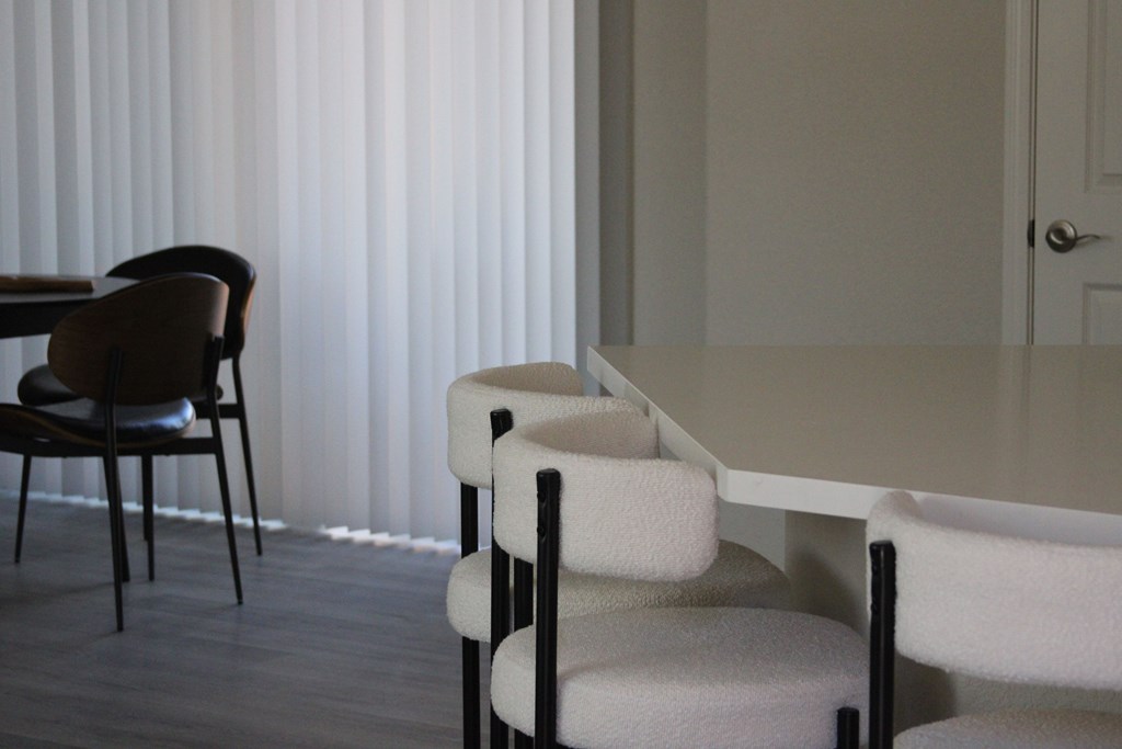 A white table with a black chair in front of a white wall.