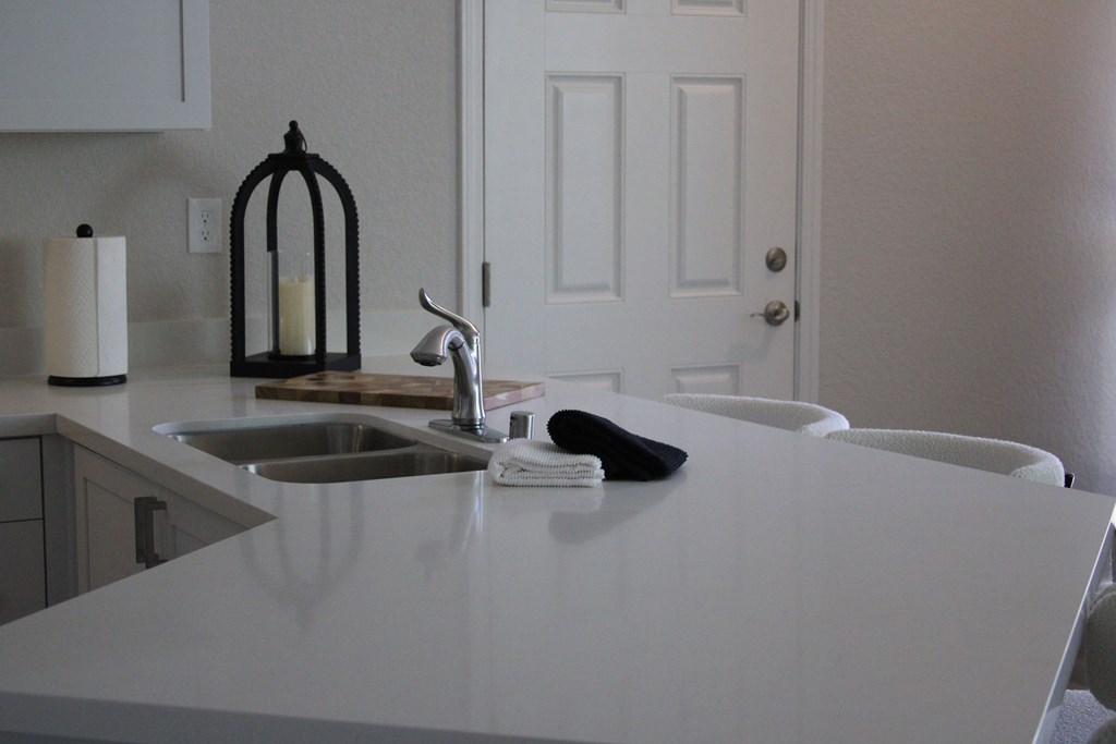 A white kitchen counter with a sink and a candle holder.