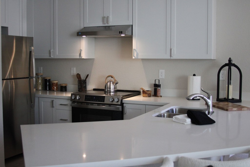A kitchen with white cabinets and a white counter top.