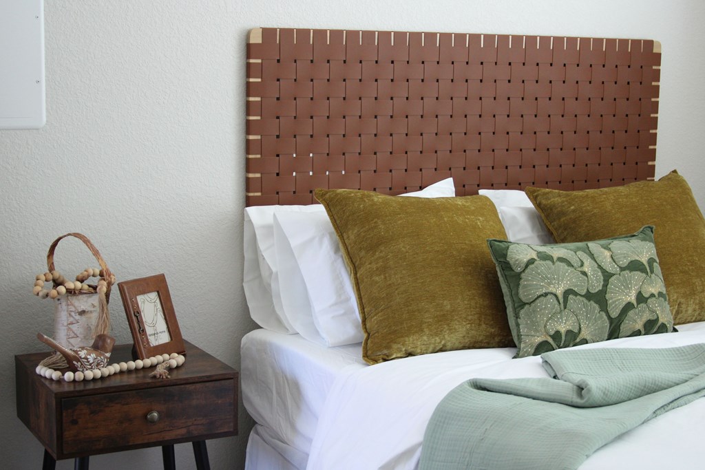 A bed with a brown headboard and white pillows with a green blanket.