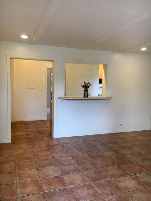 an empty living room with a counter and a mirror on the wall