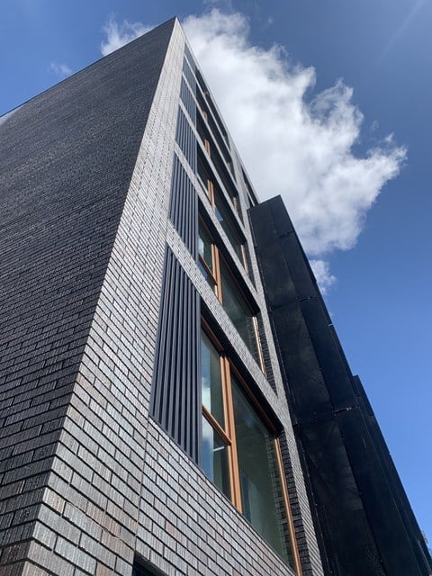 A tall building with a black facade and a large window on the side.