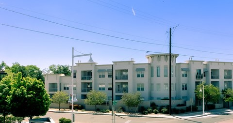 a large white apartment building with trees in front of it