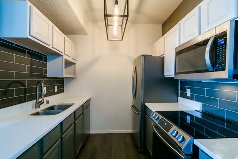 a kitchen with black and white counters and a stainless steel refrigerator