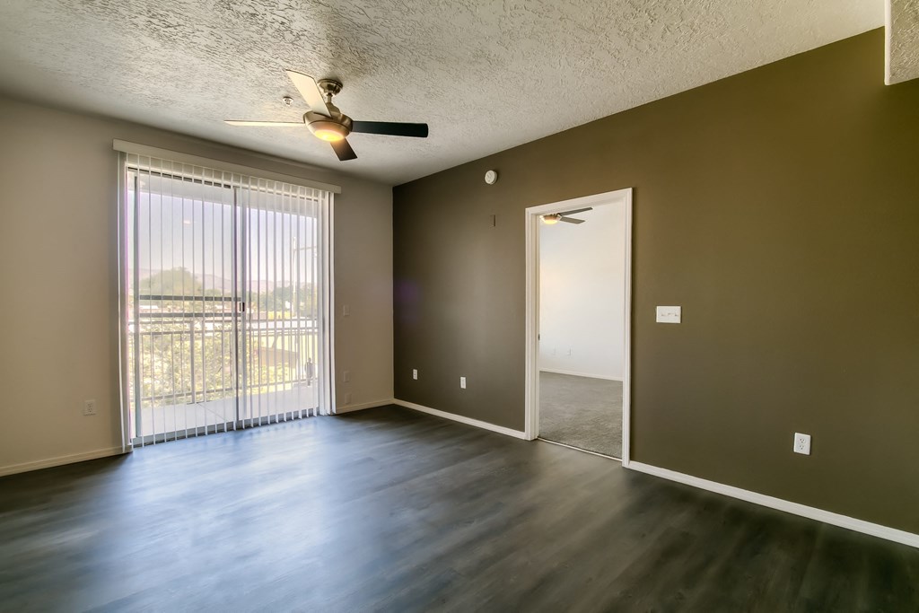 an empty living room with a sliding glass door and a ceiling fan