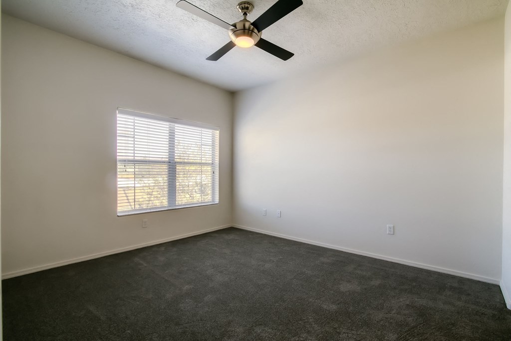 an empty room with a ceiling fan and a window