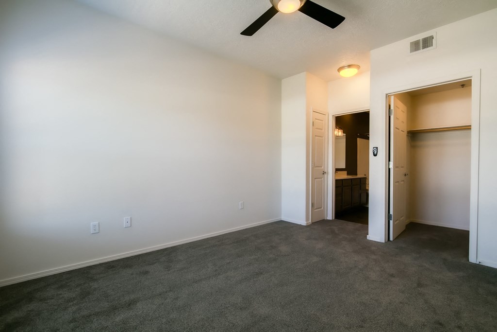 a bedroom with a ceiling fan and carpet