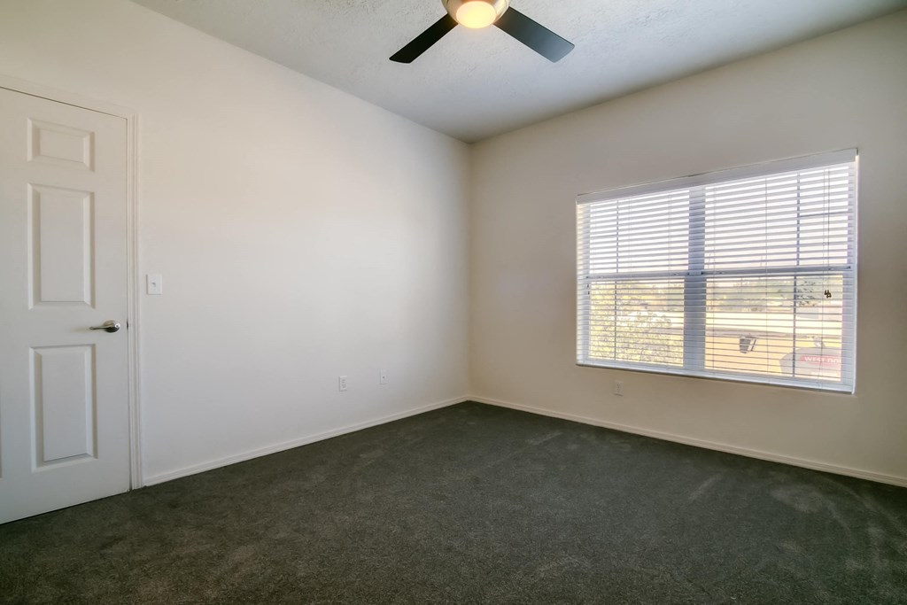 a bedroom with a large window and a ceiling fan