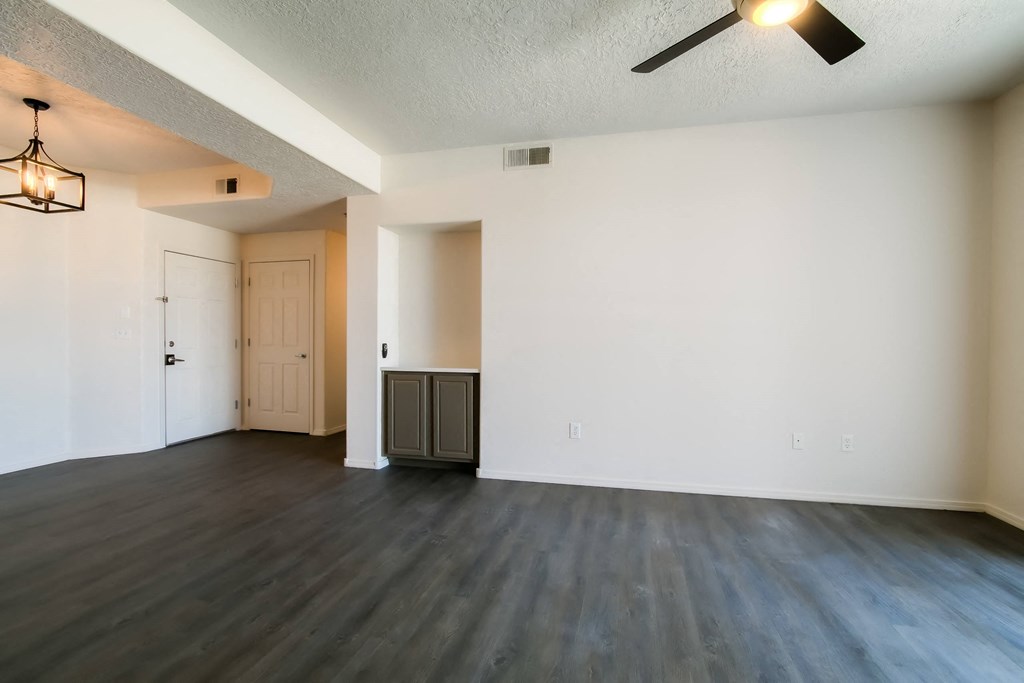 an empty living room with white walls and a ceiling fan