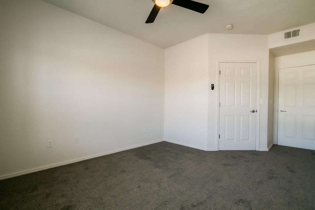 a bedroom with white walls and a ceiling fan