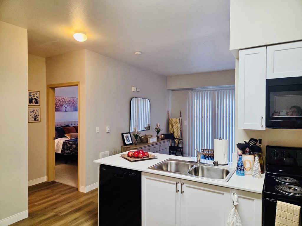 A kitchen with white cabinets and a black dishwasher.