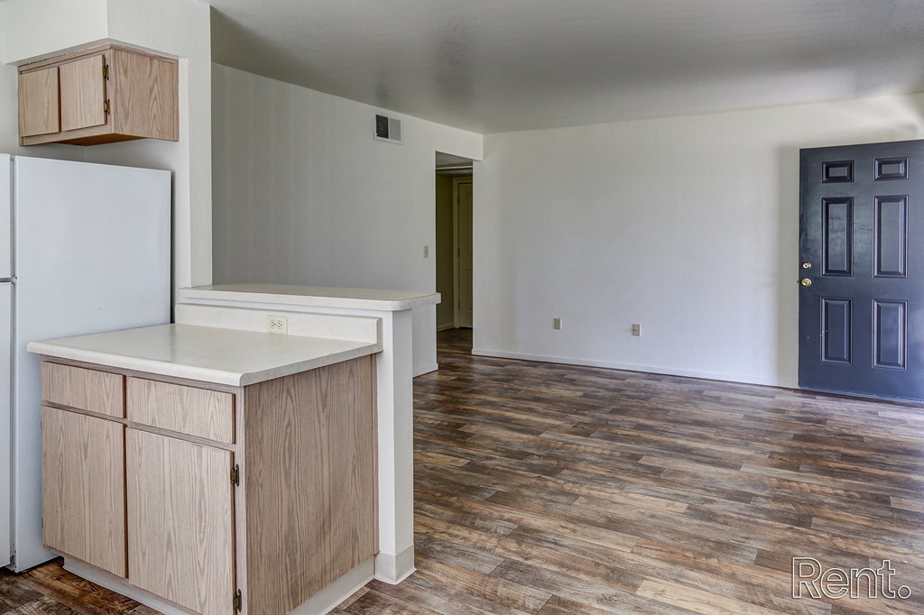 a kitchen and living room with white walls and wood floors