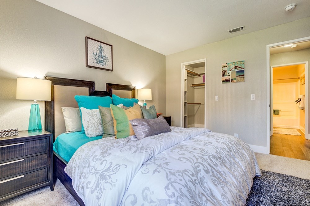 One Bedroom apartments in Pittsburg CA - Kirker Creek - Bedroom with Bed, Nightstands, Lamps, Oversized Closet, and Attached Bathroom.