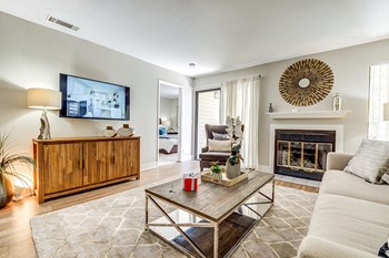 Pittsburg CA Apartments - Kirker Creek - Spacious Living Area with Wood Flooring, Sliding Glass Patio Door, Fireplace, and White Walls - Photo Gallery 2