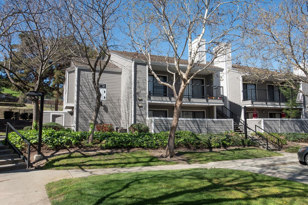 A grey building with a tree in front of it at Kirker Creek Apartments, Pittsburg, CA