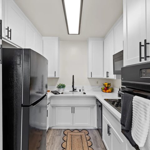 A kitchen with white cabinets and a black refrigerator.