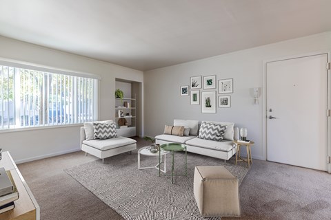 A living room with a white couch, a green coffee table, and a rug.